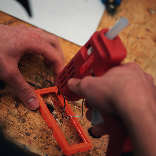 Hands bonding a broken part with a glue gun