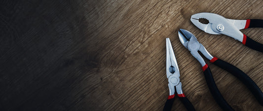 Three pairs of pliers on a wooden workbench