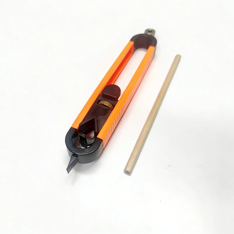 The tool seen from the pointer end: the pencil clamp, the brass-colored thumb wheel and the ribbed thumb pad on the slide, with a wooden pencil beside it