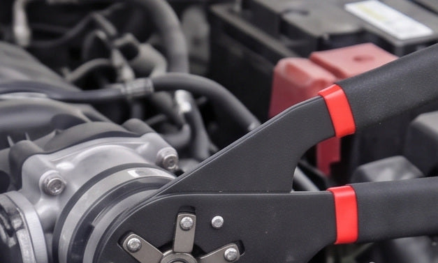 The wrench on a fitting in an engine bay