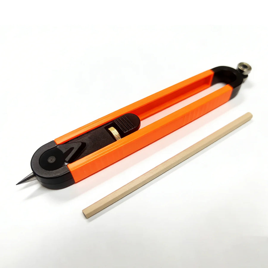 The scribing tool on a white surface with a wooden pencil beside it: orange rails, a black head with a pointer, a sliding pencil holder with a brass-colored thumb wheel, and a bearing roller at the tail