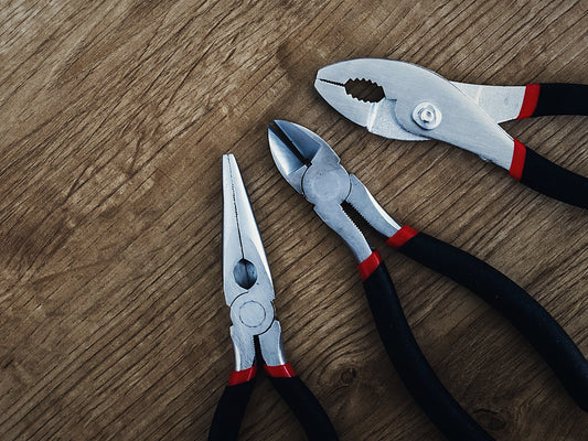 Three pairs of pliers on a wooden workbench